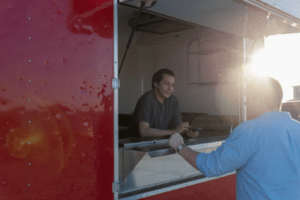 A Native entrepreneur serving a customer from his food truck, symbolizing community-driven business and economic sovereignty in Indian Country.
