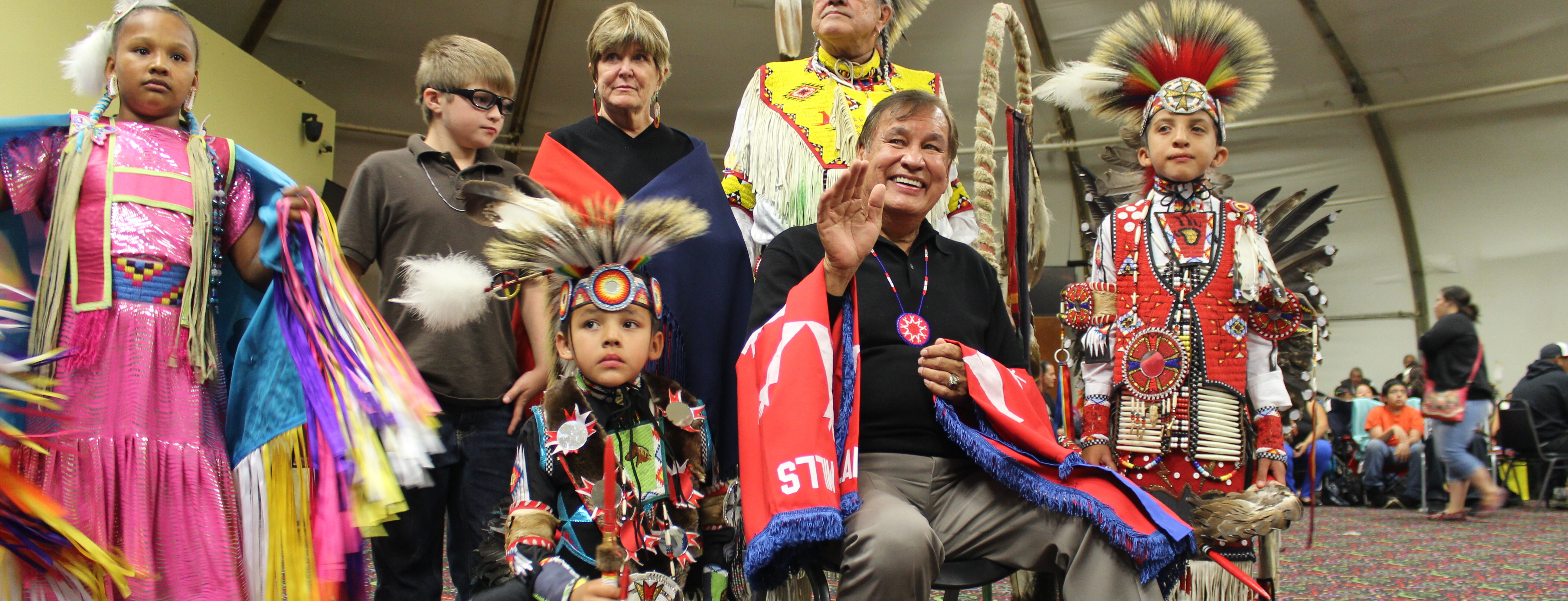 Native youth and community members in regalia at cultural celebration