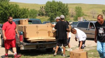 Group unloading boxes from pickup truck in Pine Ridge Indian Reservation