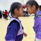 wo Native American girls in traditional regalia playing a balancing game at Oyate Ta Kola Ku Community Center.