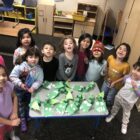 A group of children are around a table of crafts showcasing native american education.