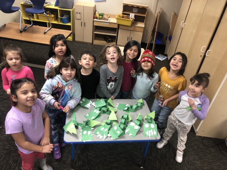 A group of children are around a table of crafts showcasing native american education.