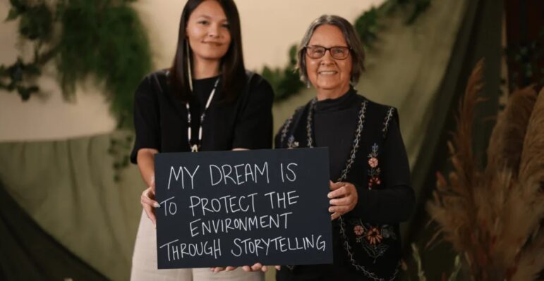 Two women are holding a sign saying, my dreams is to protect the environment through storytelling, showcasing why is environmental justice important.
