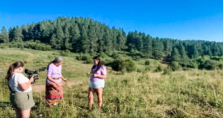 Three women standing outside, one holding a video camera showcasing why is environmental justice important.