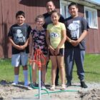 A family is standing next to their water source showcasing one of the water scarcity solutions Running Strong is providing.