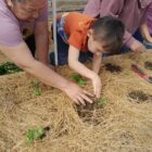 A Native American woman is helping a young boy learn how to plant crops in an effort to transform Native American food deserts.