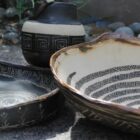 Handcrafted Native American pottery with traditional geometric designs displayed outdoors.