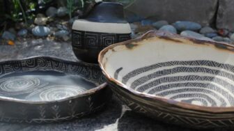 Handcrafted Native American pottery with traditional geometric designs displayed outdoors.