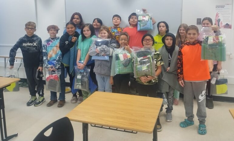 Native American children holding donated winter coats.