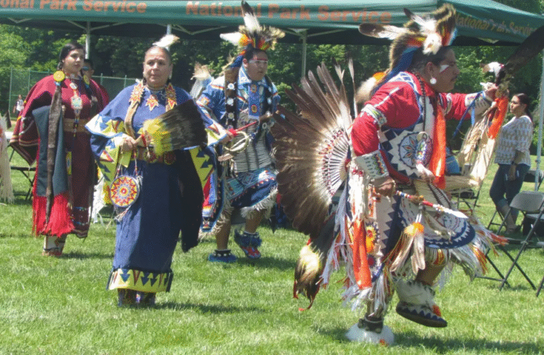 Indigenous dancers in vibrant, feathered regalia honor traditions with a performance outdoors.