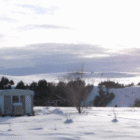 Snow-covered home on the Pine Ridge Indian Reservation during winter, showing conditions families face without heat assistance