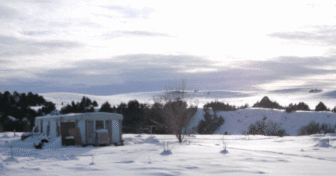 Snow-covered home on the Pine Ridge Indian Reservation during winter, showing conditions families face without heat assistance