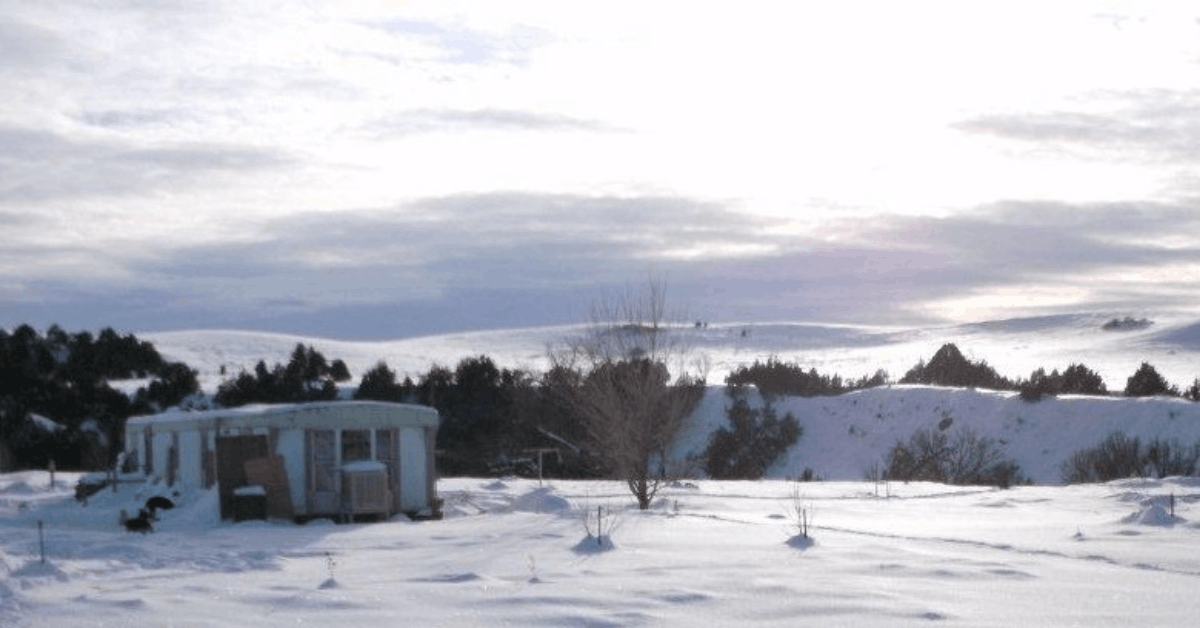 Snow-covered home on the Pine Ridge Indian Reservation during winter, showing conditions families face without heat assistance