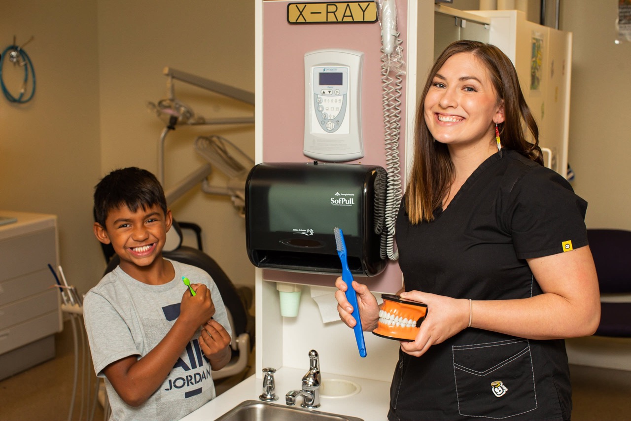 Native dentist teaching young patient proper brushing in dental clinic