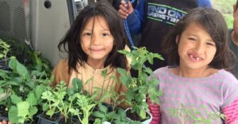 Children holding vegetable seedlings from Slim Buttes Agricultural Development program on Pine Ridge Reservation