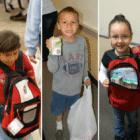 Five students holding backpacks and packaged food for Running Strong’s Smart Sacks weekend food program.