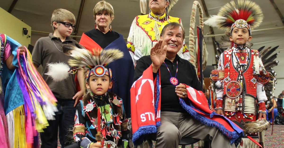 Native youth and community members in regalia at cultural celebration