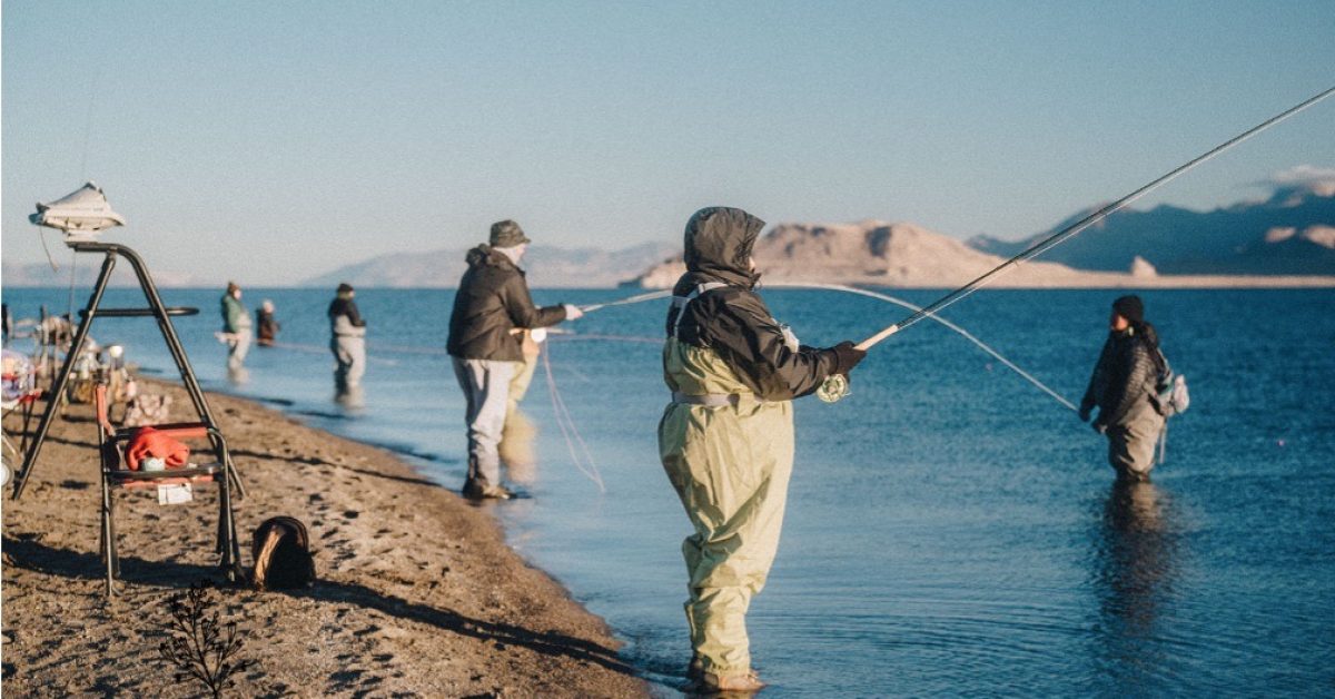 Community members fishing in cold weather by mountain lake