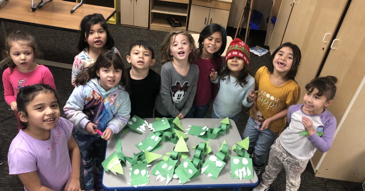A group of children are around a table of crafts showcasing native american education.