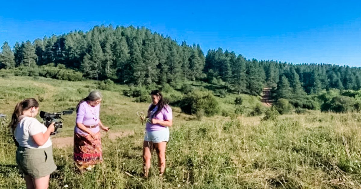 Three women standing outside, one holding a video camera showcasing why is environmental justice important.