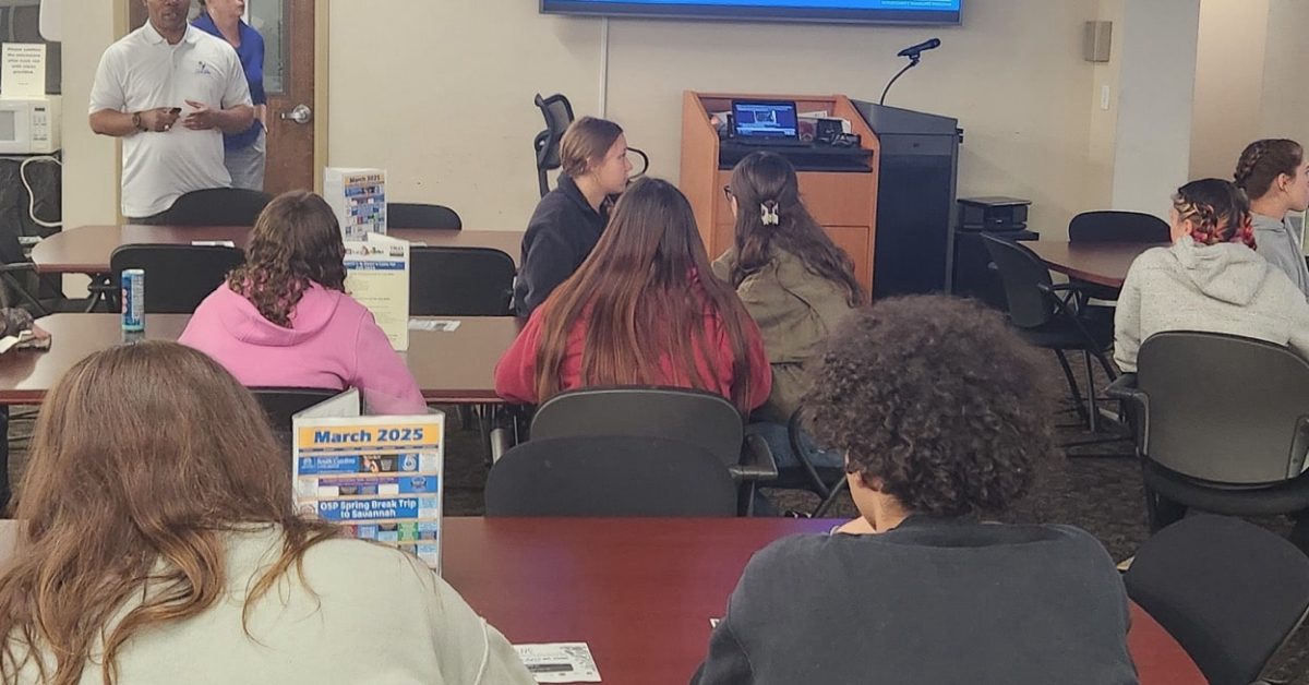 Instructor presenting to small group in classroom using large screen
