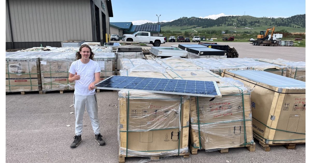 cruz and solar panels Dreamstarter recipient standing next to solar panels, working on a sustainable energy project to benefit Native communities.