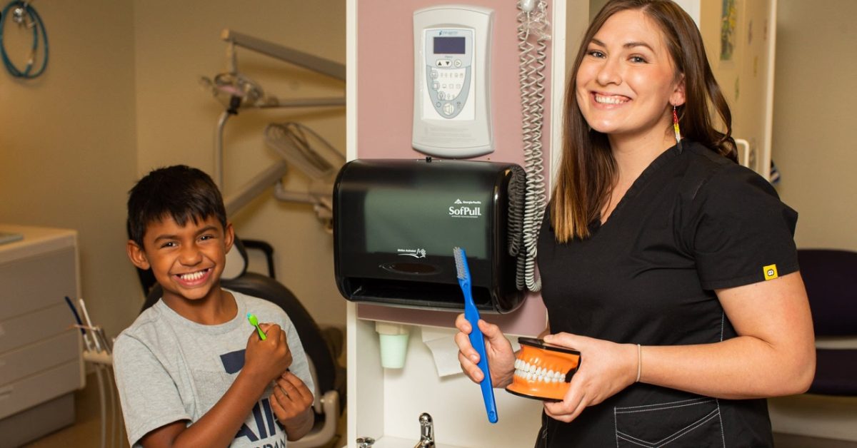 Native dentist teaching young patient proper brushing in dental clinic