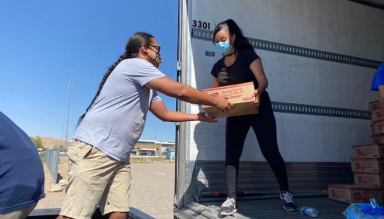 Volunteers unload boxes of food from a truck for a food security distribution, supporting Native families.