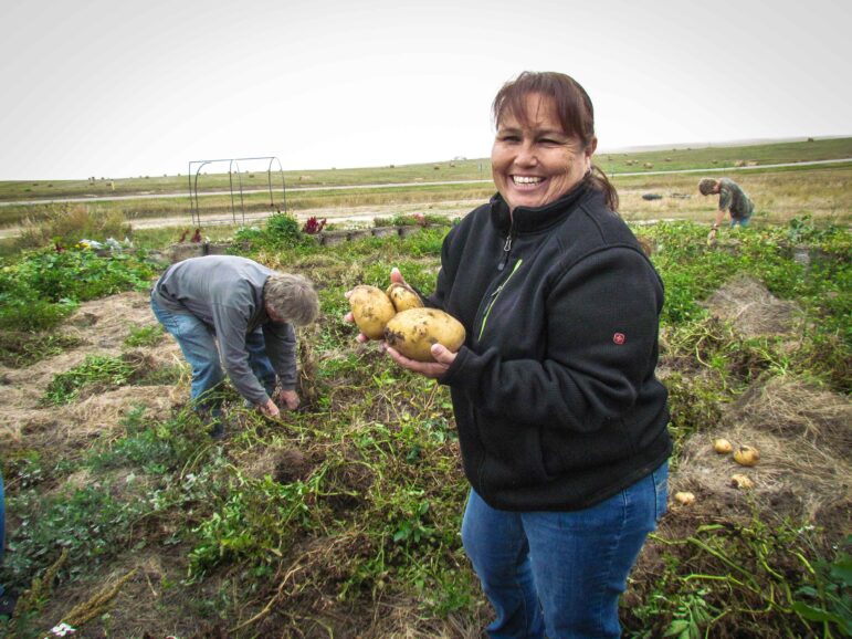 Woman smiling and holding freshly harvested potatoes from a reservation garden