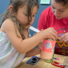 Young girl painting a craft with guidance during an arts class
