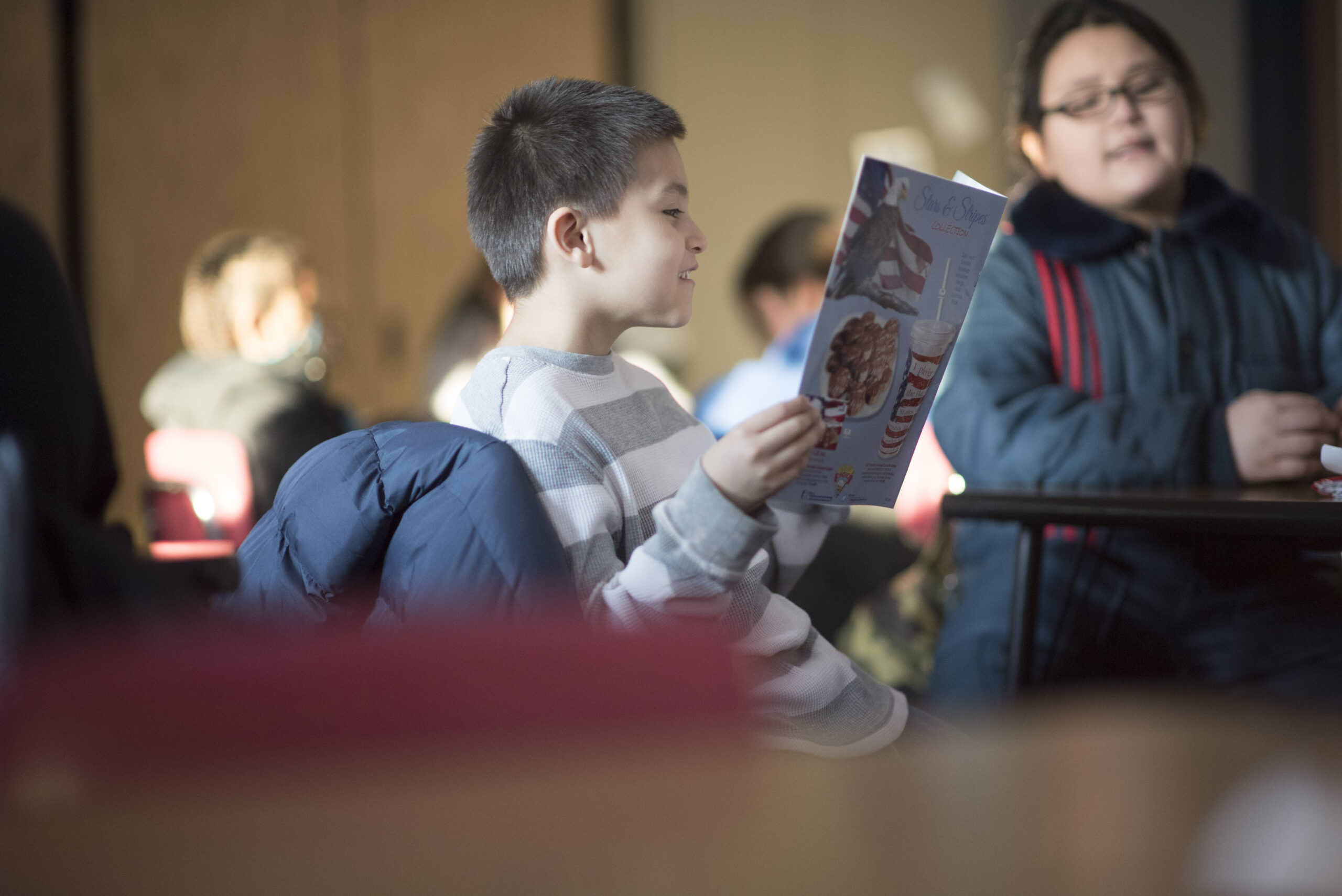 A young Native student smiles while reading a book in class.