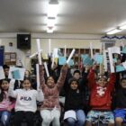 Students in a classroom holding Wailaki ABC books and rolled posters