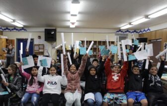 Students in a classroom holding Wailaki ABC books and rolled posters