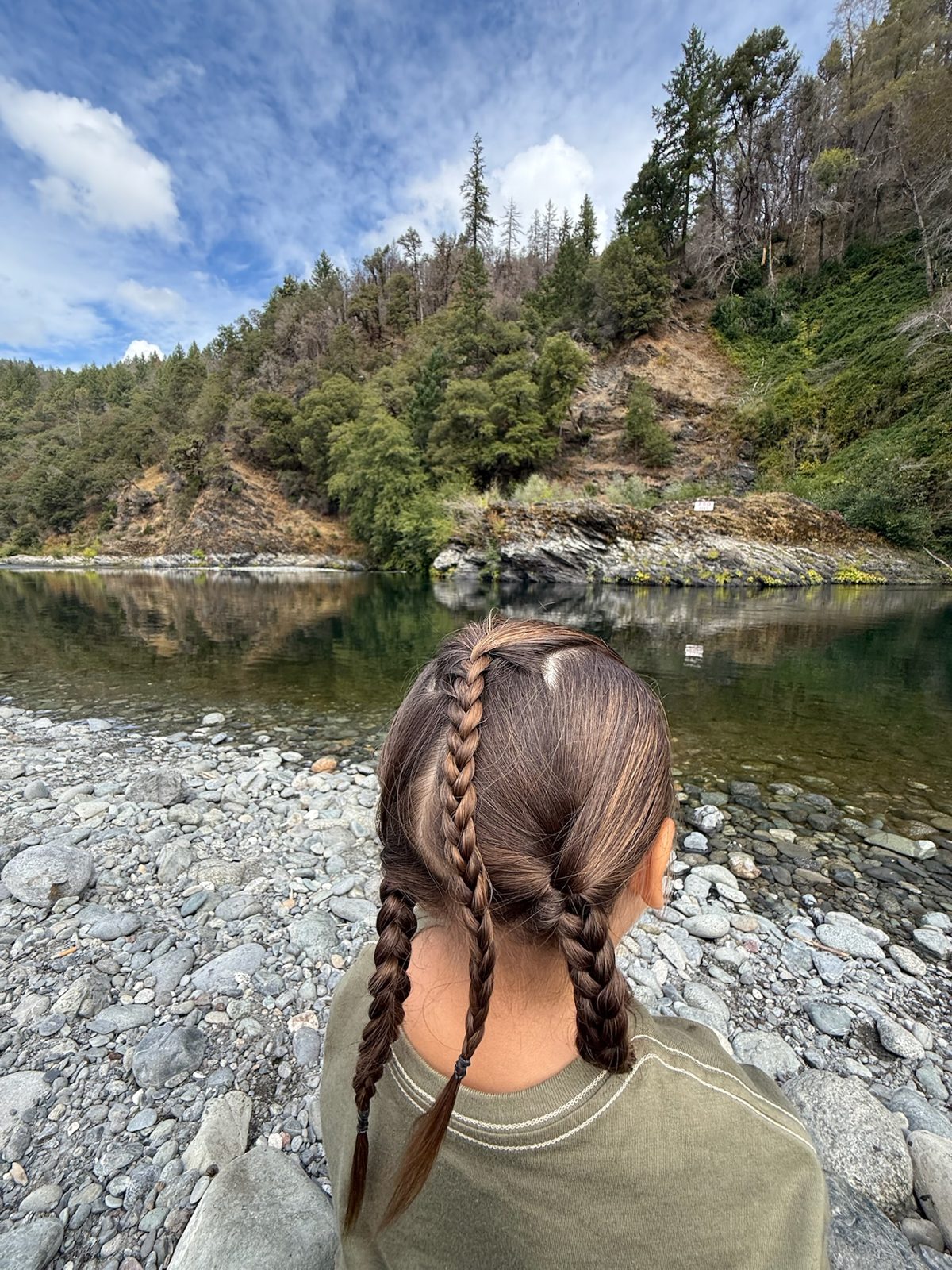 Child standing beside a river during a Hupa Language Immersion Nest outing