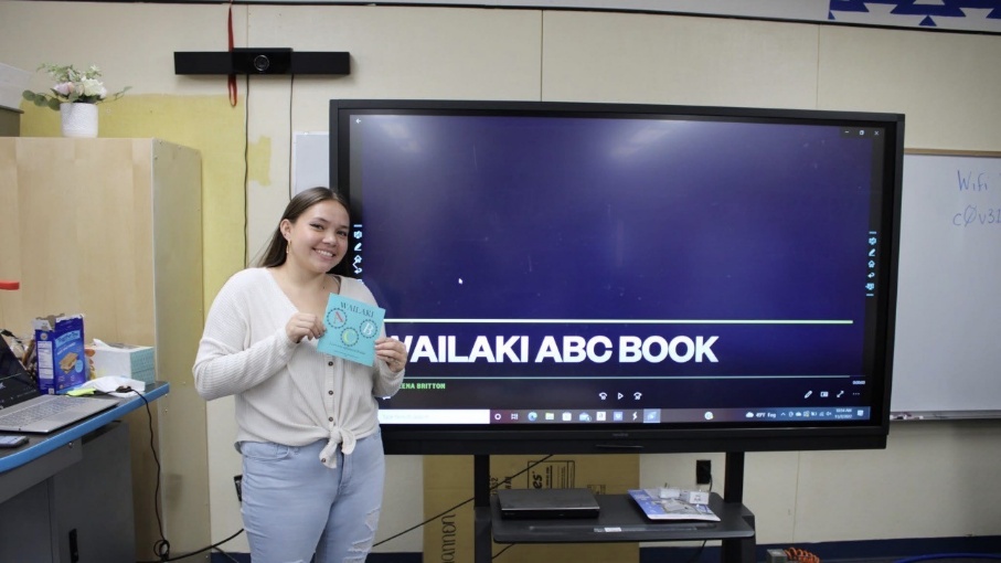 Presenter holding a Wailaki ABC book beside a classroom display