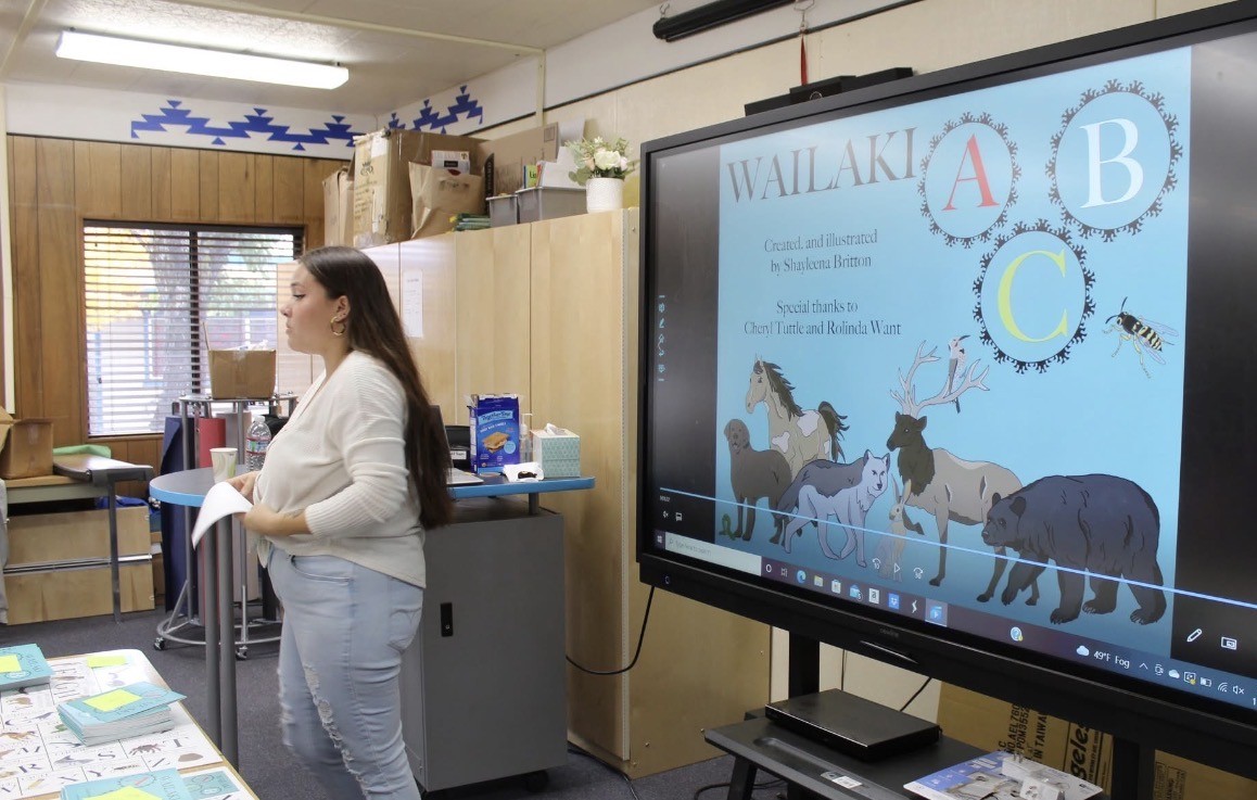 Presenter beside a classroom screen showing the illustrated Wailaki ABC book cover