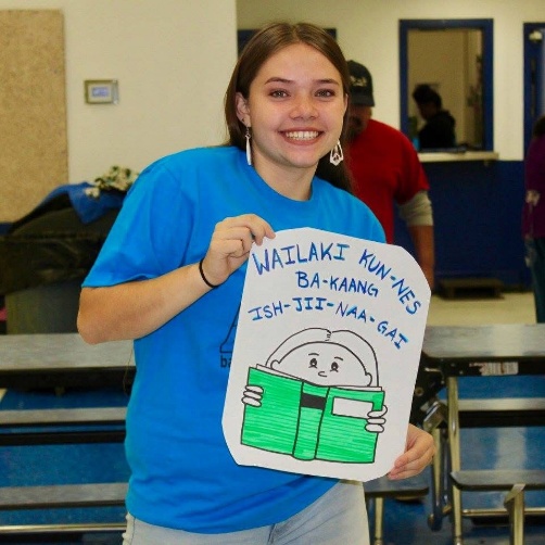 Participant holding an illustrated Wailaki language learning poster