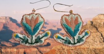Two floral beaded earrings against a canyon backdrop