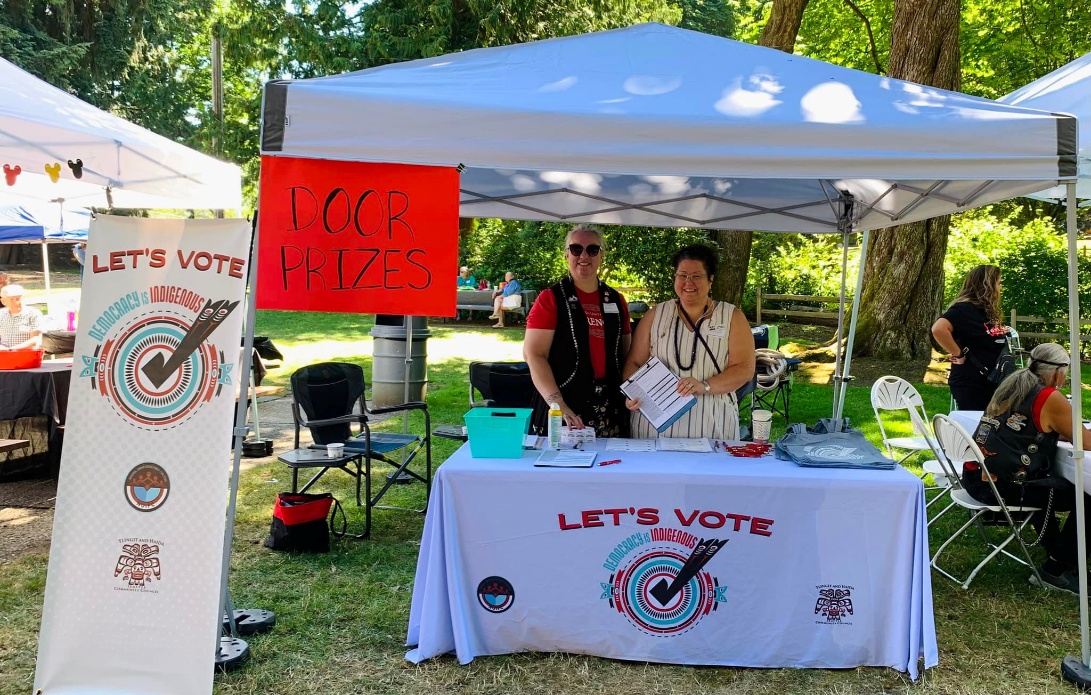 Community members staffing a voter outreach table at an outdoor event.