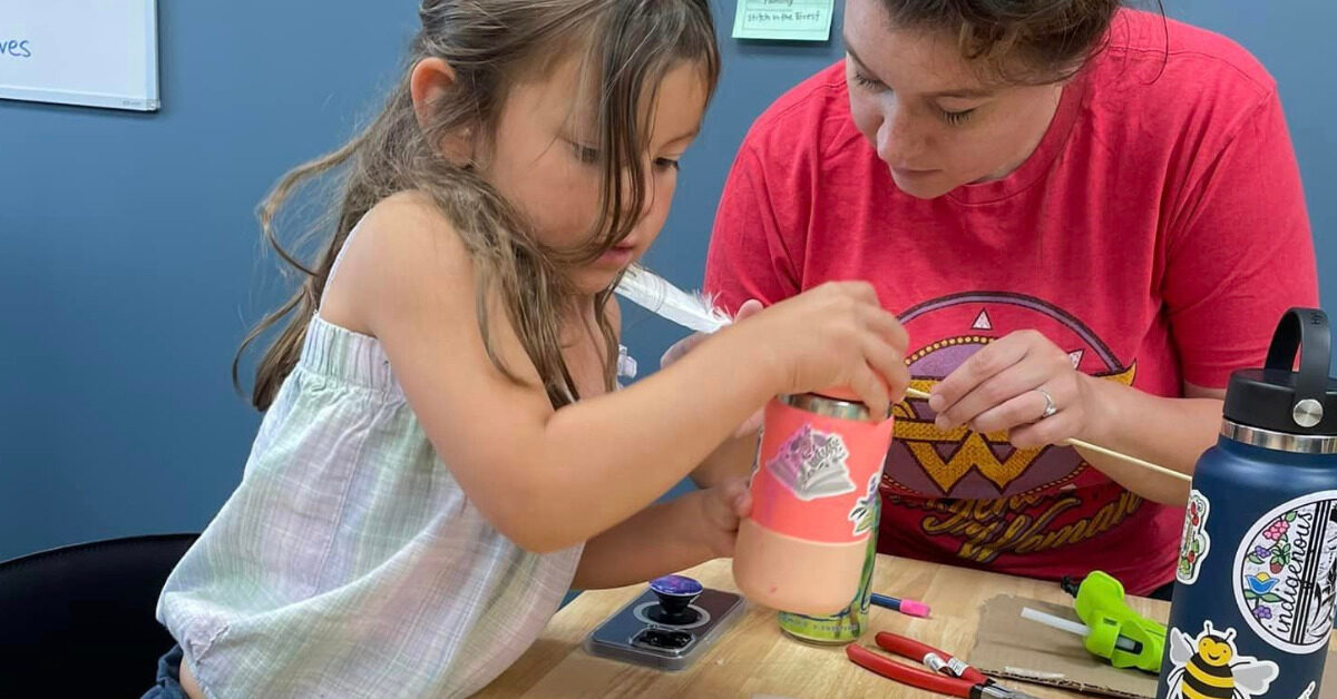 Young girl painting a craft with guidance during an arts class